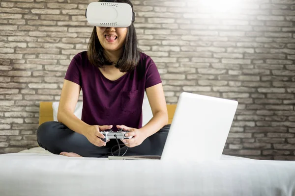 Mutlu gülümseyen genç kadın evde yatakta 360 Vr kulaklık gözlük sanal gerçekliğin kullanırken en iyi deneyimleri elde ederken oyun oynama