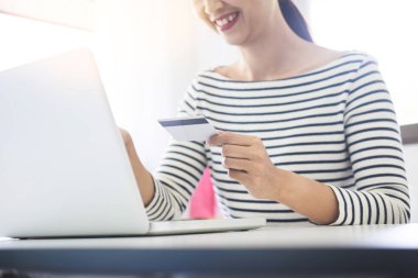 Online alışveriş kavramı. mutlu genç holding smartphone ve dizüstü bilgisayar ile kredi kartı ile satın almak için ödediği el.