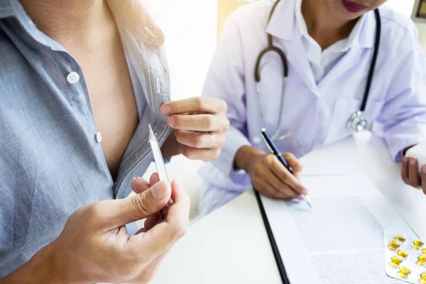 Doctor with a thermometer in his hand taking patient\'s in hospital, medical concept.