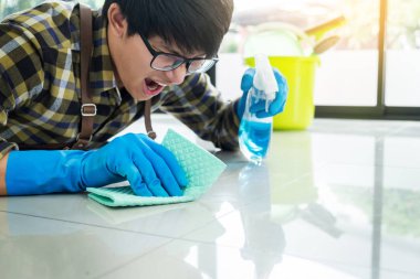 adam evinde zemin temizleme bezi ile bez ve akıcı bir sprey kullanır.