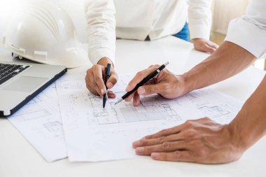 Yakın çekim, kişinin mühendis el çizim planı üzerinde mavi baskı mimar ekipmanlı, mimarlar tablo, takım çalışması ve iş akışı inşaat kavramı tartışmaya.