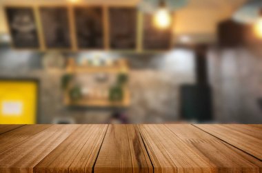 Seçilen odak boş kahverengi ahşap masa ve kahve dükkanı veya restaurent bokeh görüntü ile arka plan bulanıklık. Fotomontaj veya ürün ekran