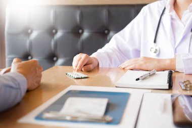 Tablet ilacın tutan el doktor ve hasta hastane odasında açıklamak.