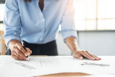 Kişinin el çizim planı üzerinde mavi baskı mimar donanımları ile masada çalışan mimar mühendis