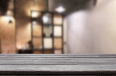 Seçilen odak boş kahverengi ahşap masa ve kahve dükkanı veya restaurent bokeh görüntü ile arka plan bulanıklık. Fotomontaj veya ürün ekran.