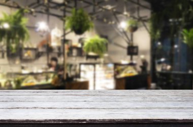 Seçilen odak boş kahverengi ahşap masa ve kahve dükkanı veya restaurent bokeh görüntü ile arka plan bulanıklık. Fotomontaj veya ürün ekran.