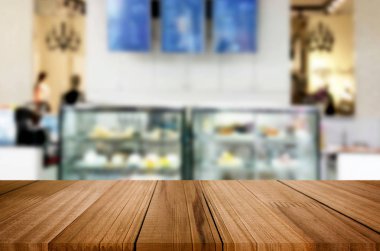 Seçilen odak boş kahverengi ahşap masa ve kahve dükkanı veya restaurent bokeh görüntü ile arka plan bulanıklık. Fotomontaj veya ürün ekran.