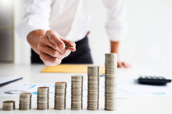 Midsection of businessman hand put stacking coins at on Increasing coin office desk, Currency, Investment, Savings, financial concept.