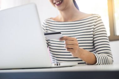 Online alışveriş kavramı. mutlu genç holding smartphone ve dizüstü bilgisayar ile kredi kartı ile satın almak için ödediği el.