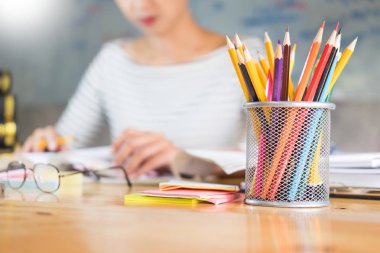 Çekici kız üstünde defter fornt formüller ile bir tahta bir sınıfta okumak ve ahşap masa başına oturmuş