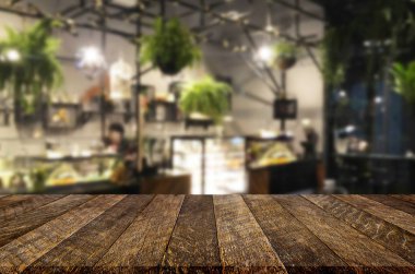 Seçilen odak boş kahverengi ahşap masa ve kahve dükkanı veya restaurent bokeh görüntü ile arka plan bulanıklık. Fotomontaj veya ürün ekran.