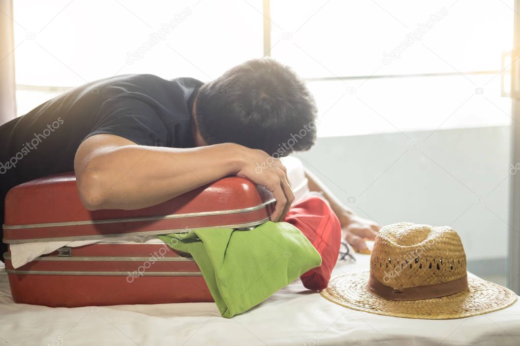 man trying to fit all clothing to packing his red suitcase before vacation