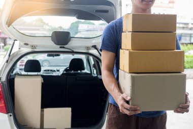 Teslimat yükleyici postacı karton kutu yığını tutan veya paket van car yakınındaki bir kamyonun önünde dururken taşıyan mavi üniformalı