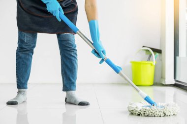 Genç hizmetçi paspas ve plastik kova fırçalar, eldiven ve deterjanlar ile eşi yardımcı bırakarak Oda ev yerde tutarak yere mobbing Temizleme