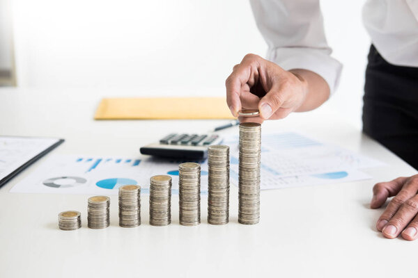 Midsection of businessman hand put stacking coins at on Increasing coin office desk, Currency, Investment, Savings, financial concept.