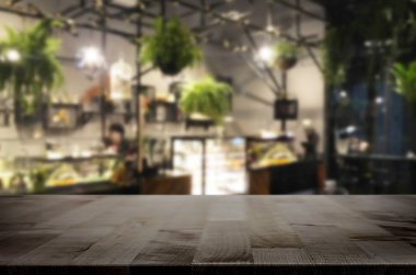 Seçilen odak boş kahverengi ahşap masa ve kahve dükkanı veya restaurent bokeh görüntü ile arka plan bulanıklık. Fotomontaj veya ürün ekran.