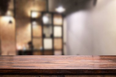 Seçilen odak boş kahverengi ahşap masa ve kahve dükkanı veya restaurent bokeh görüntü ile arka plan bulanıklık. Fotomontaj veya ürün ekran.