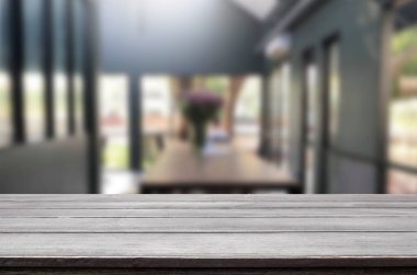 Seçilen odak boş kahverengi ahşap masa ve kahve dükkanı veya restaurent bokeh görüntü ile arka plan bulanıklık. Fotomontaj veya ürün ekran