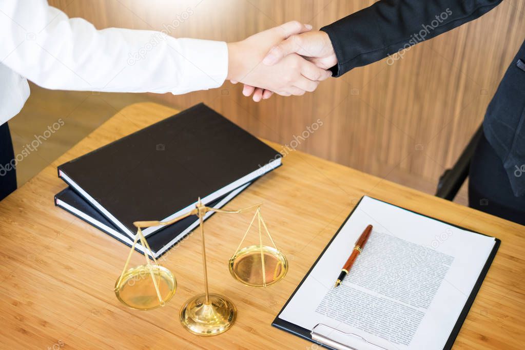 Gavel Justice hammer on wooden table with judge and client shaking hands after adviced in background at courtroom, lawyer service concept 