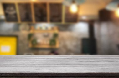Seçilen odak boş kahverengi ahşap masa ve kahve dükkanı veya restaurent bokeh görüntü ile arka plan bulanıklık. Fotomontaj veya ürün ekran