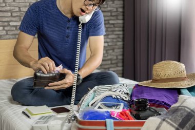 Genç adam hurring kadar toplantı ve seyahat bavul evde telefonla konuşurken ve hazırlık için ambalaj not alma.