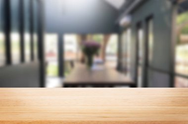 Seçilen odak boş kahverengi ahşap masa ve kahve dükkanı veya restaurent bokeh görüntü ile arka plan bulanıklık. Fotomontaj veya ürün ekran