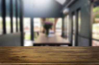 Seçilen odak boş kahverengi ahşap masa ve kahve dükkanı veya restaurent bokeh görüntü ile arka plan bulanıklık. Fotomontaj veya ürün ekran