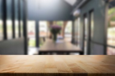 Seçilen odak boş kahverengi ahşap masa ve kahve dükkanı veya restaurent bokeh görüntü ile arka plan bulanıklık. Fotomontaj veya ürün ekran