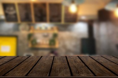 Seçilen odak boş kahverengi ahşap masa ve kahve dükkanı veya restaurent bokeh görüntü ile arka plan bulanıklık. Fotomontaj veya ürün ekran