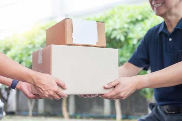 Woman receiving parcel cardboard box from delivery man Carrying Courier Shipping Mail from making an online order while standing in front of the house