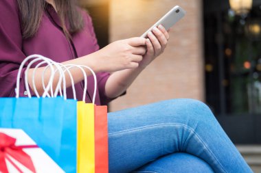 Bir gün alışveriş tadını çıkarırken cep telefonu ile alışveriş merkezinde paperbags bak kadın
