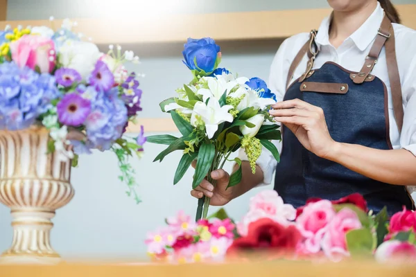 Güzel yapay buket çiçek mağazası, iş, satış ve floristik el sanatları ve el yelek yapmak düzenleme kullanarak iş yerinde kadın çiçekçi kavramı yapılan