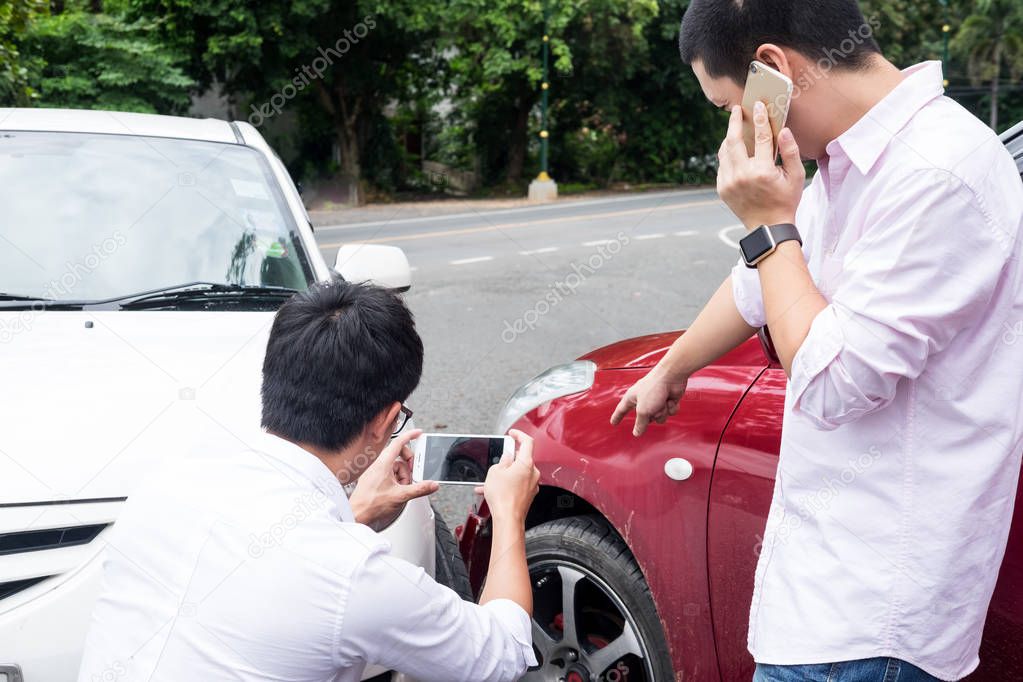 Male Driver take pictures of accident-damaged vehicle with a  holding  smartphone After Traffic Collision proof of insurance claim.