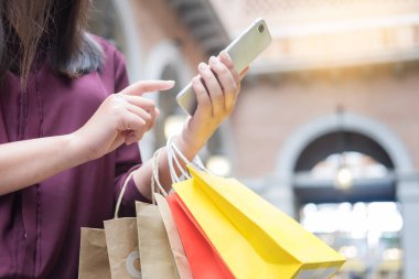 Bir gün alışveriş tadını çıkarırken cep telefonu ile alışveriş merkezinde paperbags bak kadın