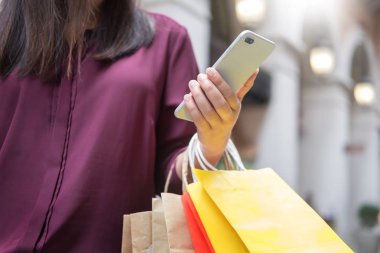 Bir gün alışveriş tadını çıkarırken cep telefonu ile alışveriş merkezinde paperbags bak kadın