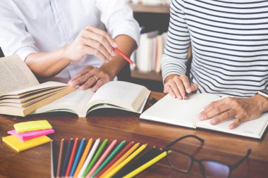 Genç öğrenciler sınıf çalışma kitabı yakalamak ve bir Kütüphane, eğitim ve okul kavramı özel ders öğrenme arkadaş yardım.