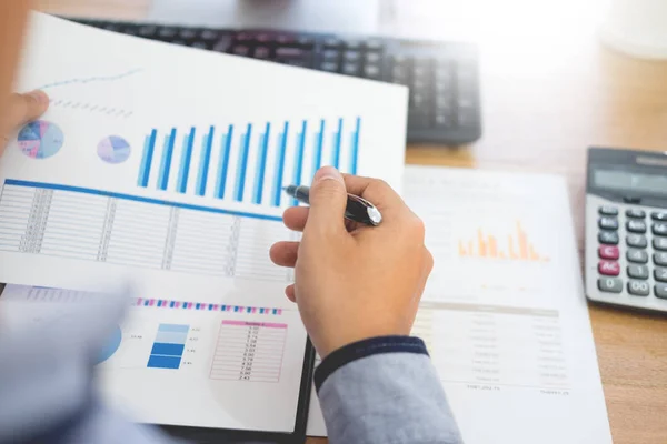 business man working on a laptop tablet and graph data documents on his desk in home office