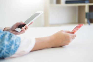 Online alışveriş kavramı. mutlu genç holding smartphone ve dizüstü bilgisayar ile kredi kartı ile satın almak için ödediği el.