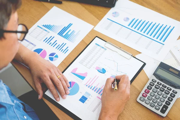 business man working on a laptop tablet and graph data documents on his desk in home office