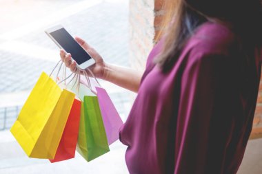 Bir gün alışveriş tadını çıkarırken cep telefonu ile alışveriş merkezinde paperbags bak kadın