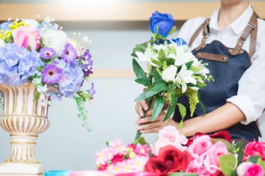 Güzel yapay buket çiçek mağazası, iş, satış ve floristik el sanatları ve el yelek yapmak düzenleme kullanarak iş yerinde kadın çiçekçi kavramı yapılan
