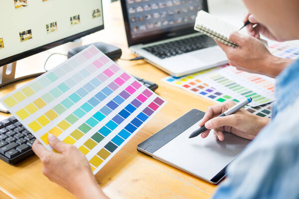 young couple sitting at the table and working together of creative designers working at the studio doing some retouching on a creative project.