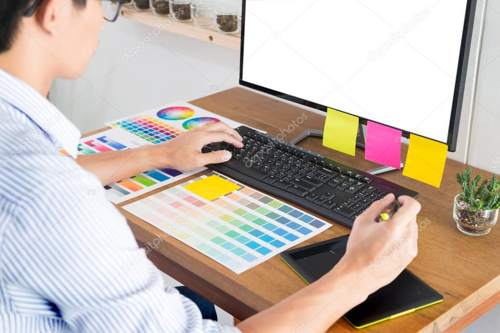 Graphic designer or creative holding Mouse and do his work material color pantone swatch samples art tools at desk in office 