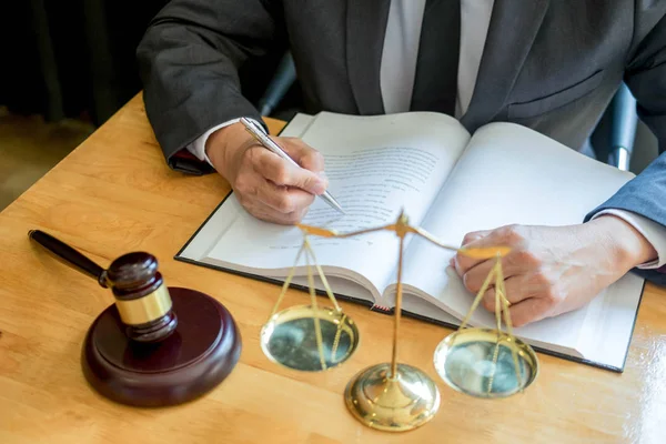 Abogado masculino trabajando con papeles contractuales y leyendo libro de leyes en —  Fotos de Stock