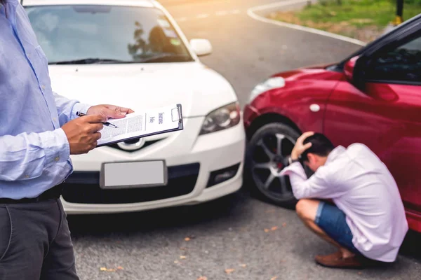 Agente de seguros que escribe en el portapapeles mientras examina el coche después de un — Foto de Stock