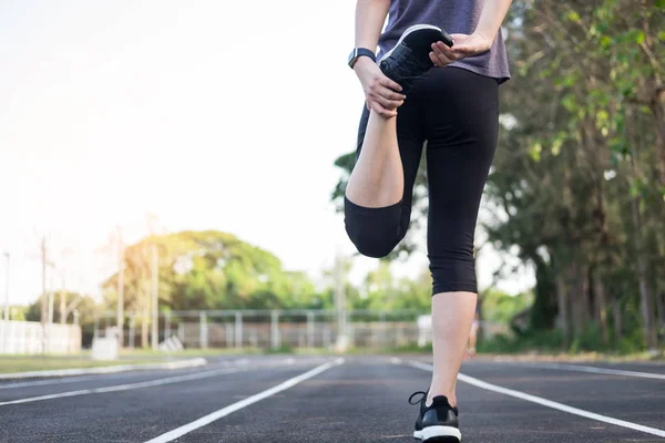 Concetto fitness. Giovane donna fitness che allunga le gambe e si prepara a correre sul pavimento allo stadio . — Foto Stock