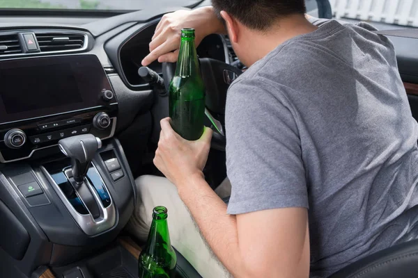 ドライブの概念のために飲んではいけない、若い酔った男は、危険な車を運転中にビールやアルコールのボトルを飲みます. — ストック写真