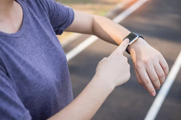 Donne esercizio al mattino utilizzando guardando sui suoi orologi intelligenti — Foto Stock