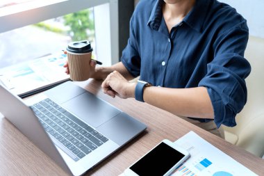 Dizüstü bilgisayar ve belgelerde grafik verileri ile çalışan iş adamı 