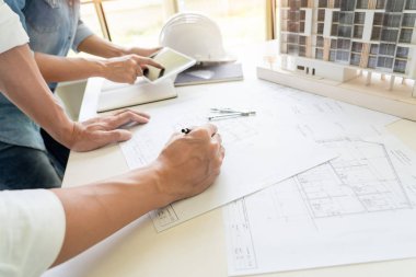 Mimarlar mühendis planı ile masada tartışıyor, takım